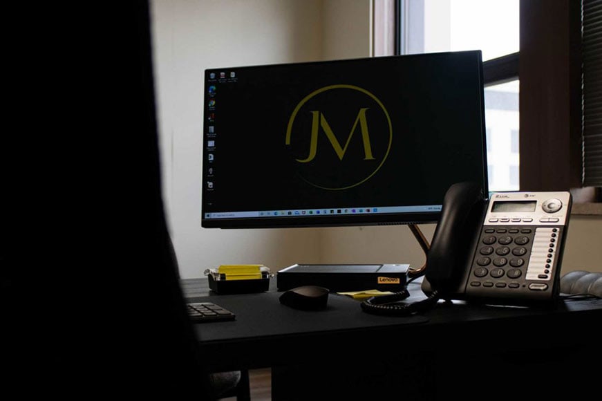 Desk with computer monitor displaying law firm's logo.